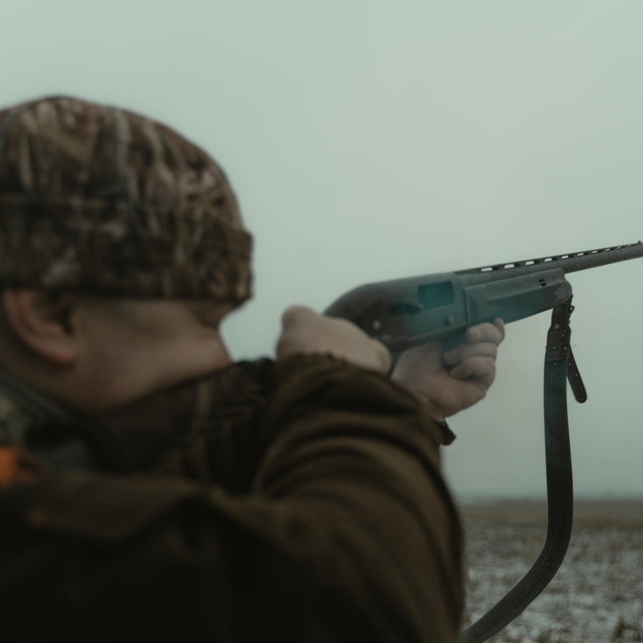 A man holding a shotgun hunting.
