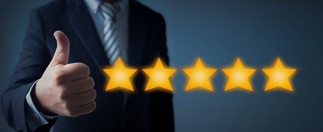 A man in a suit and tie is giving a thumbs up in front of five stars.
