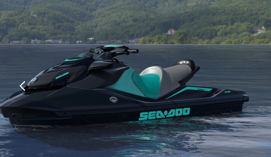 Black and teal Sea-Doo jet ski on calm water with forested hills in the background