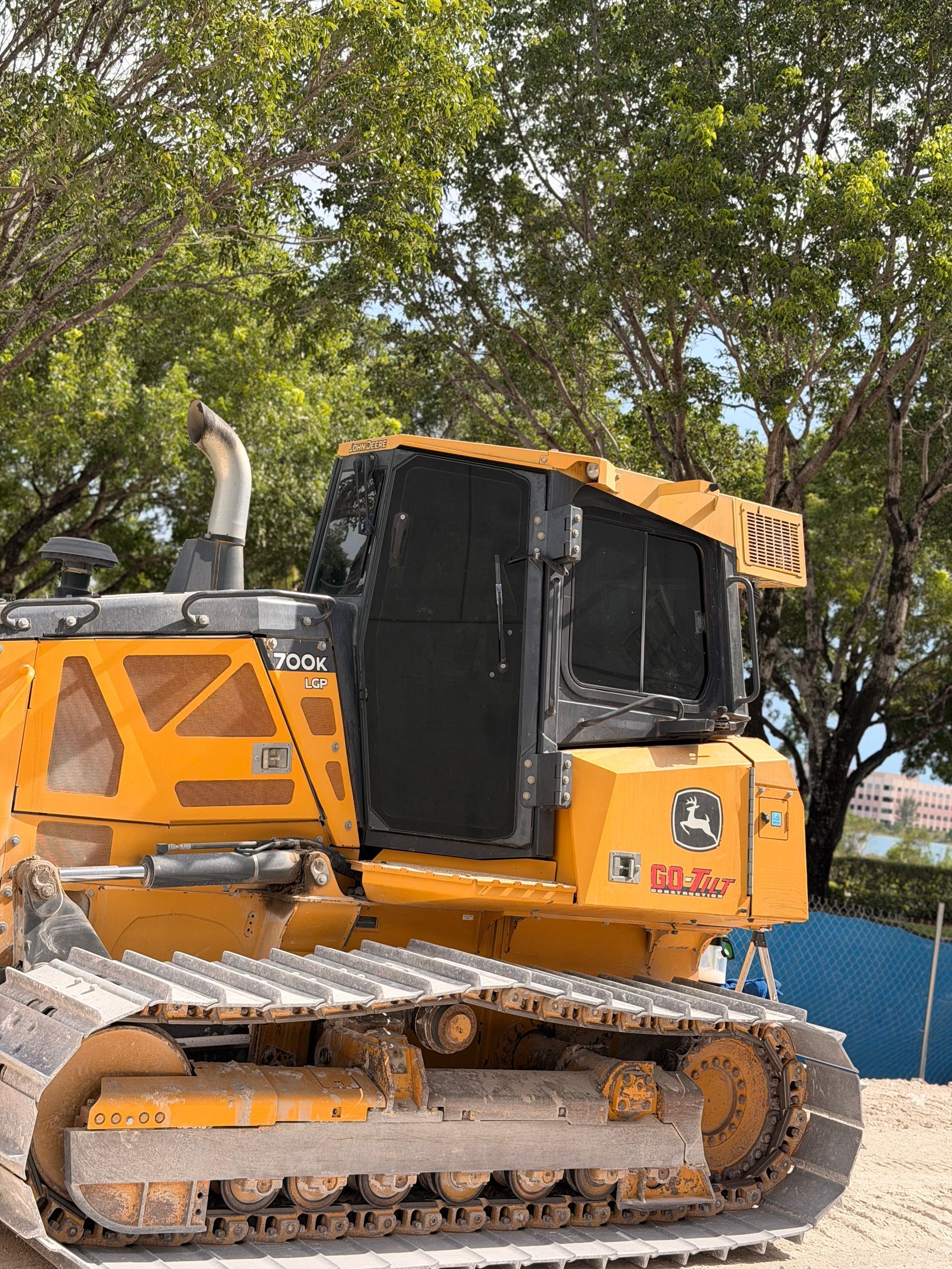Orange tracked construction vehicle parked outdoors under trees