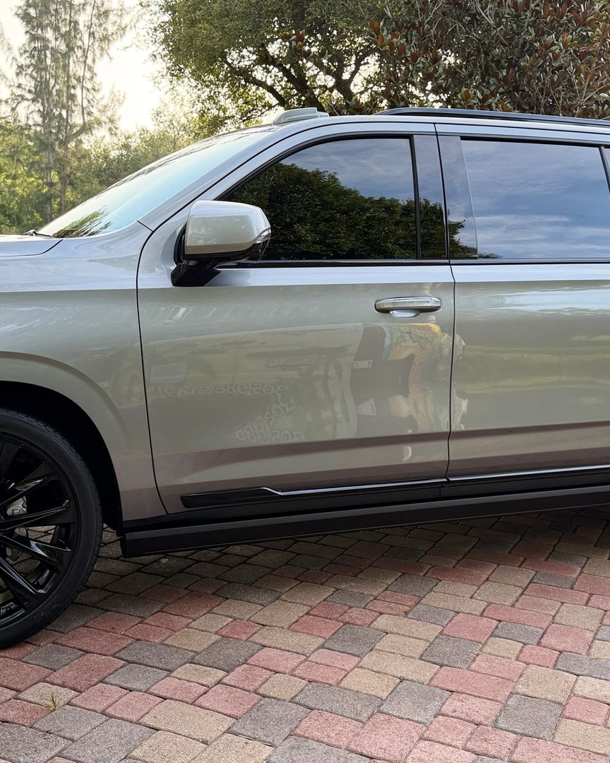 Silver SUV parked on a brick driveway with dark tinted windows and black wheels.