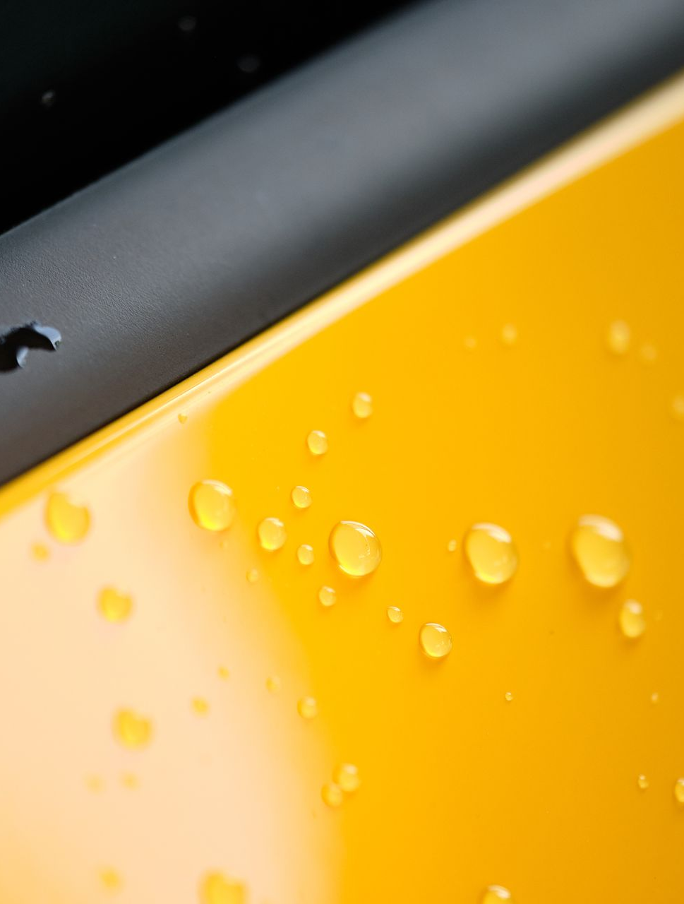 Yellow car door with water droplets, black trim visible.