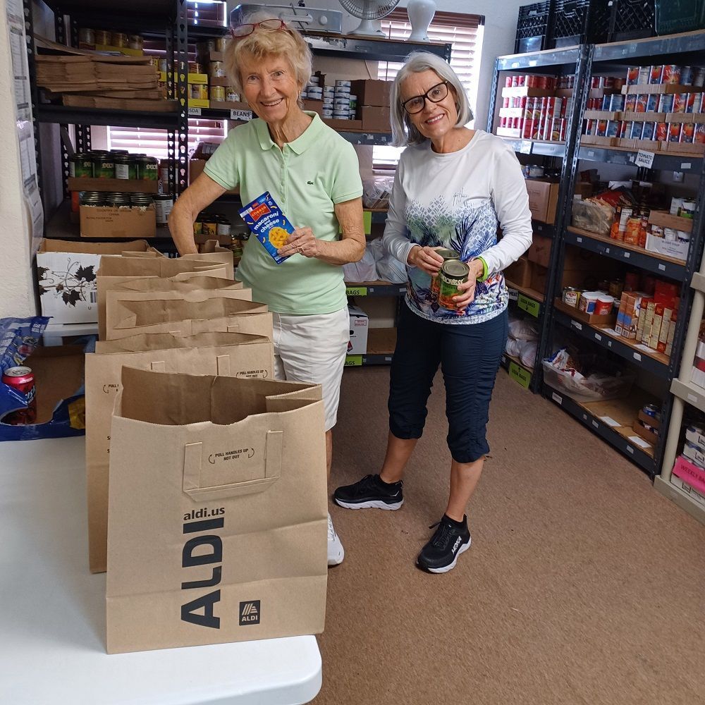 Two volunteers preparing bags of food to distribute at the CROS Delray Beach Food Pantry.