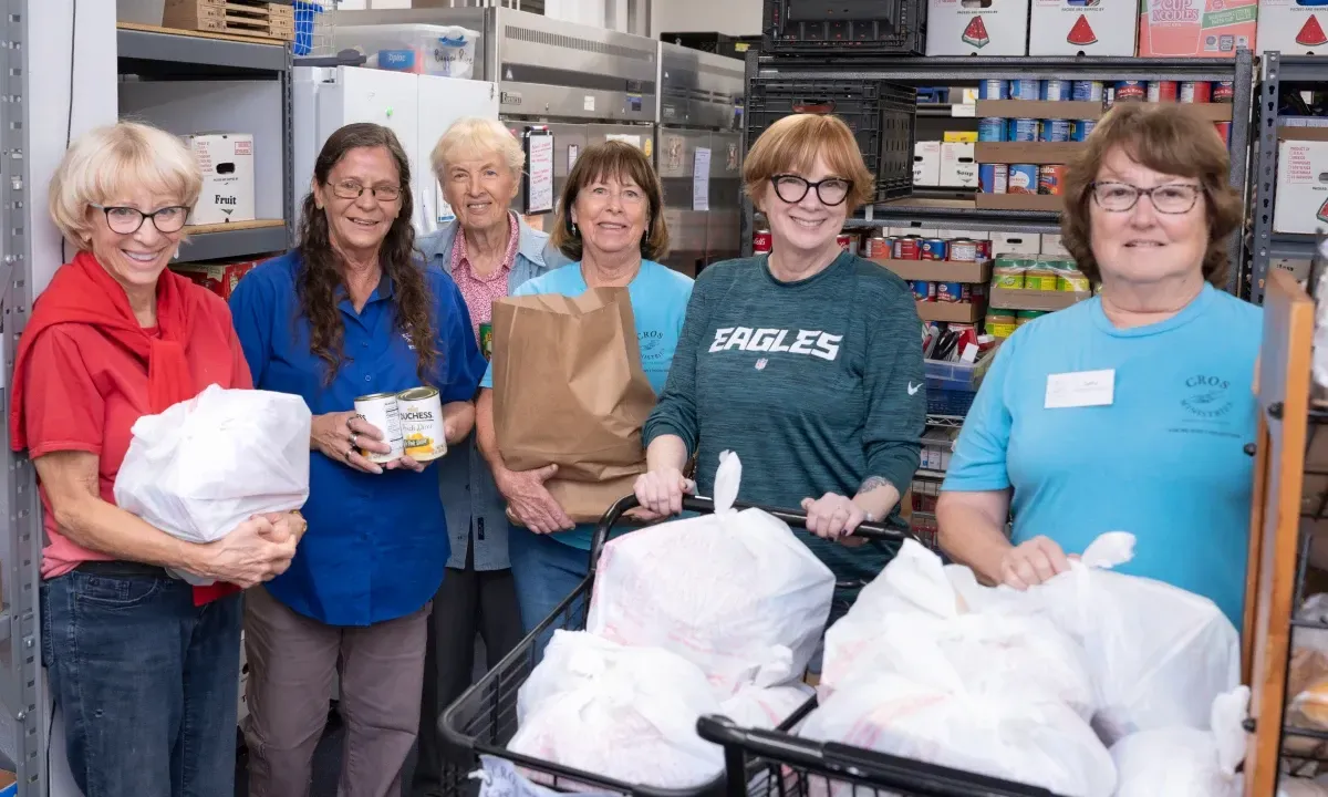 Two volunteers preparing bags of food to distribute at the CROS Delray Beach Food Pantry.