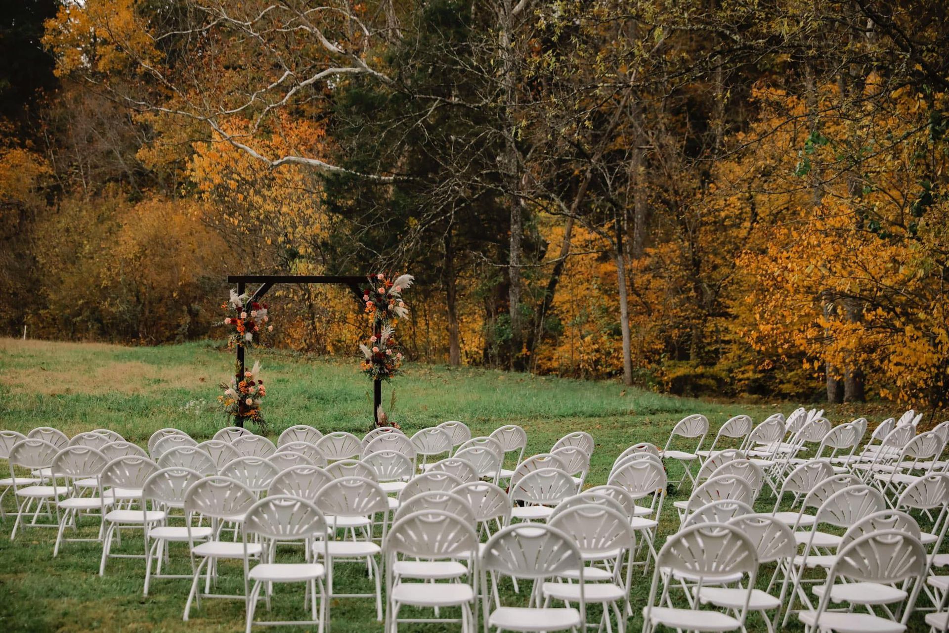 A row of folding chairs are lined up in a field.