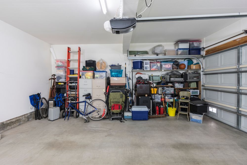 A tidy garage with shelves, tools, ladders, a bicycle, and a closed overhead door.