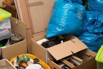 Packed storage area with cardboard boxes, blue bags, and assorted household items.