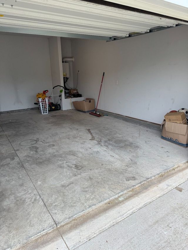 Empty concrete garage with a partly open door and a few boxes against the back wall