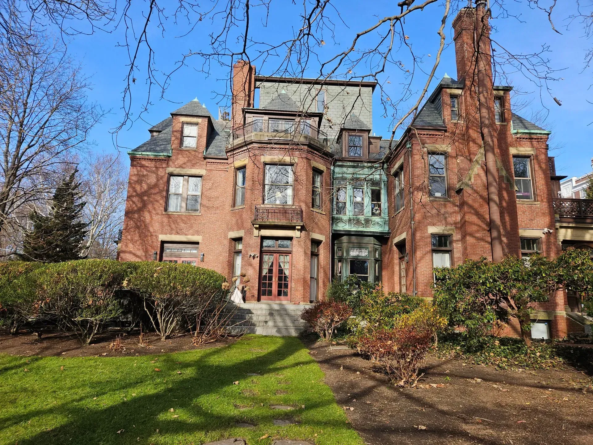 A man is standing on a ladder on the side of a brick building.