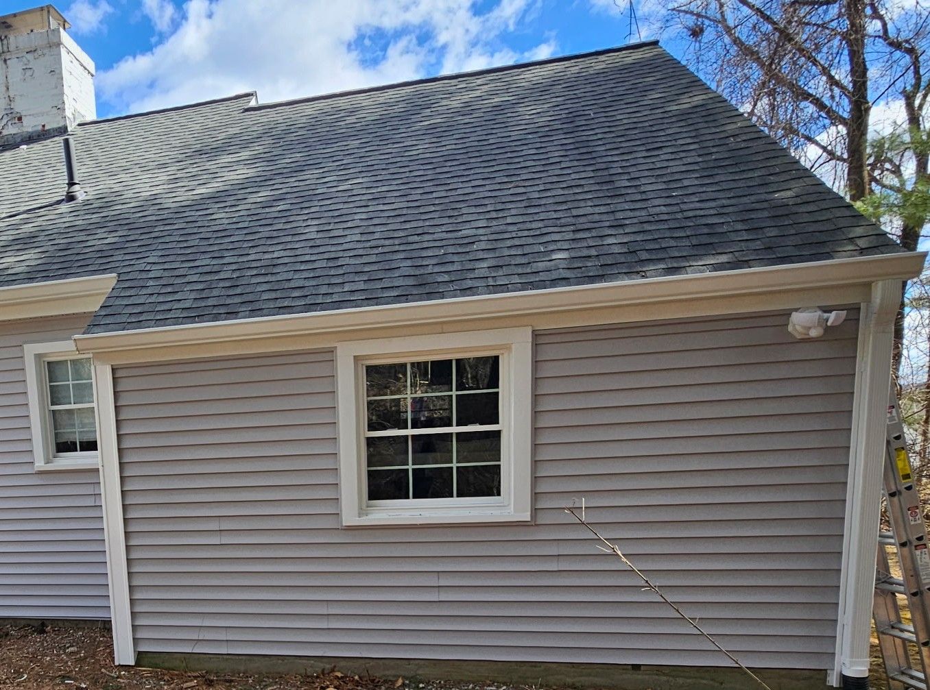 Custom 6-inch seamless K-style aluminum gutter installation on a home in Bedford, New Hampshire, installed beneath the roof drip edge for proper water collection. The high-capacity gutter system features oversized 3x4 downspouts designed to improve drainage, reduce overflow during heavy rain, and protect the home's foundation, siding, and landscaping.