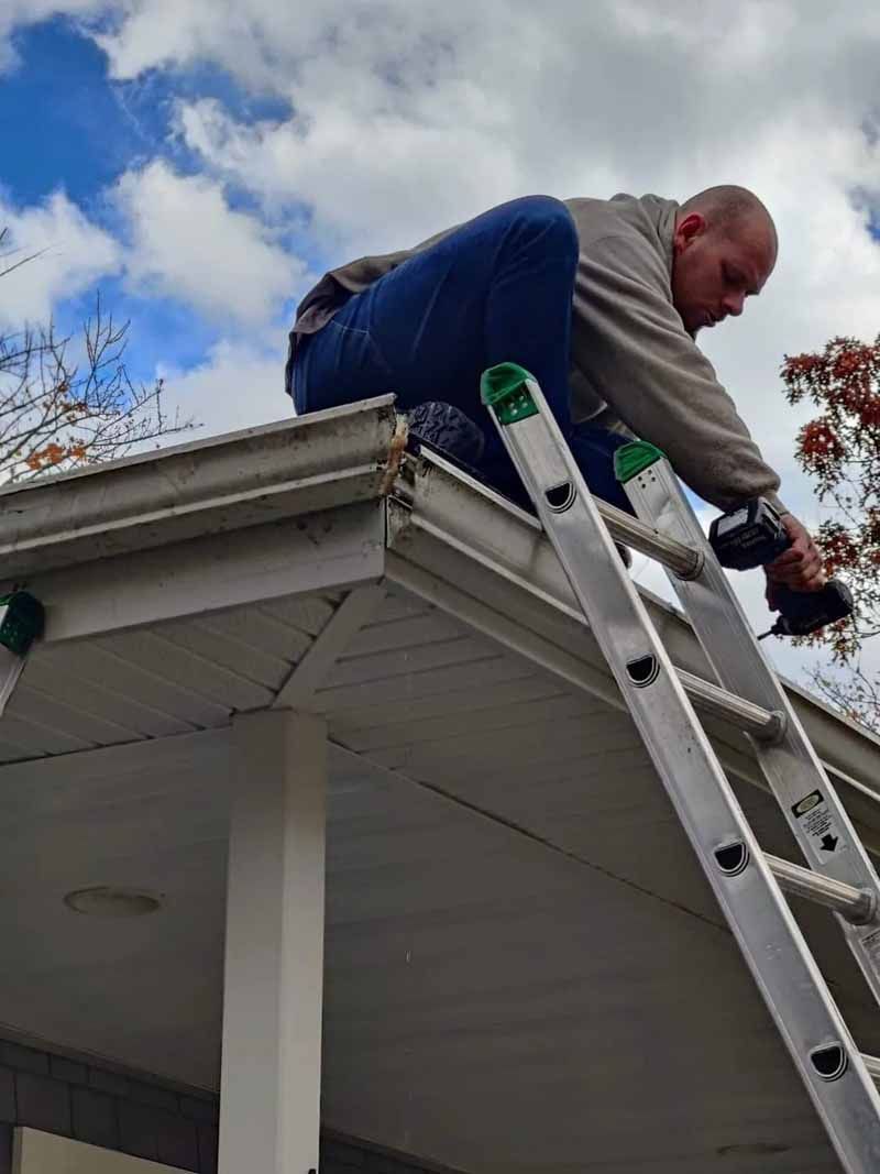 Crew repairing fascia board and installing trim alongside 5-inch K-style seamless gutter