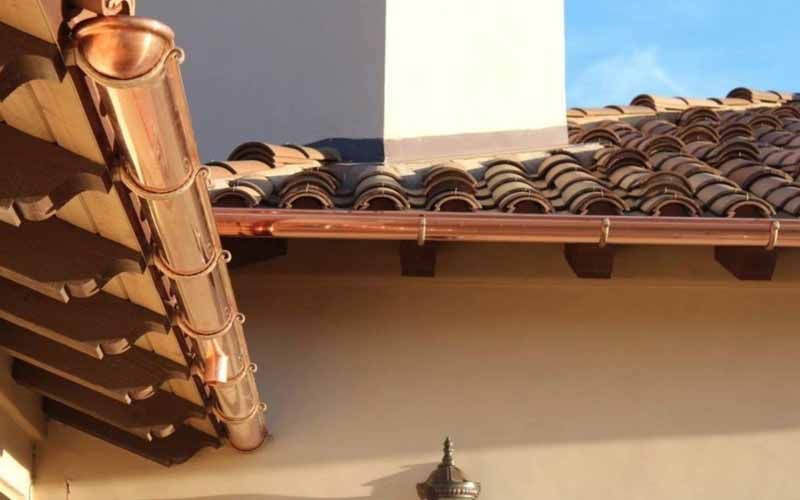 A copper gutter is attached to the roof of a building