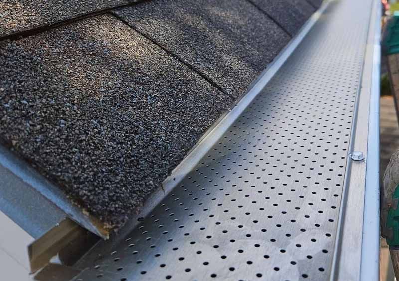Leaves and debris prevented from entering gutter by perforated guard system