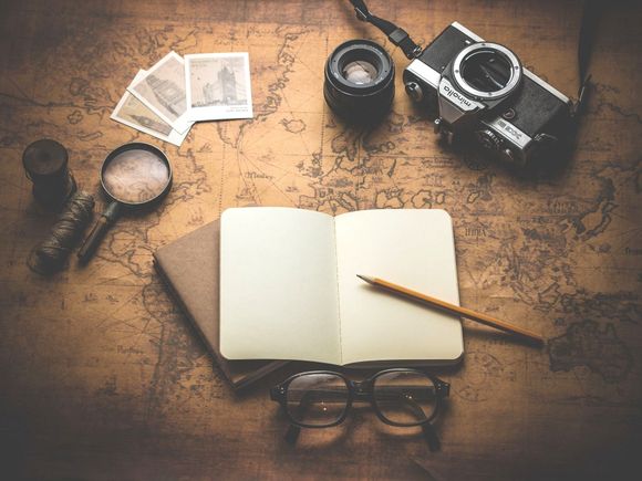 An open book with a pencil and a camera on a map.