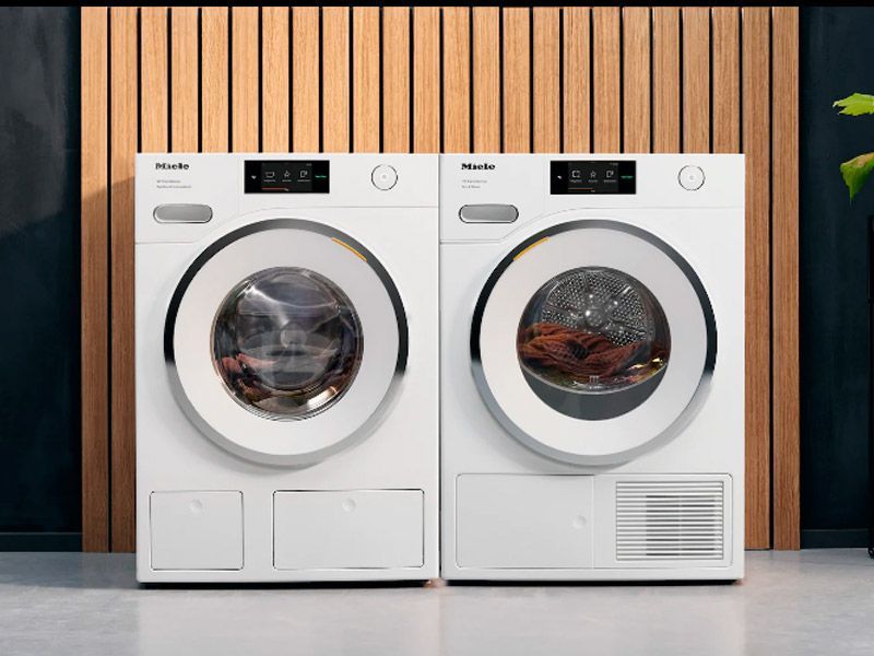White washing machine in a bathroom, with towels and a brush on top.