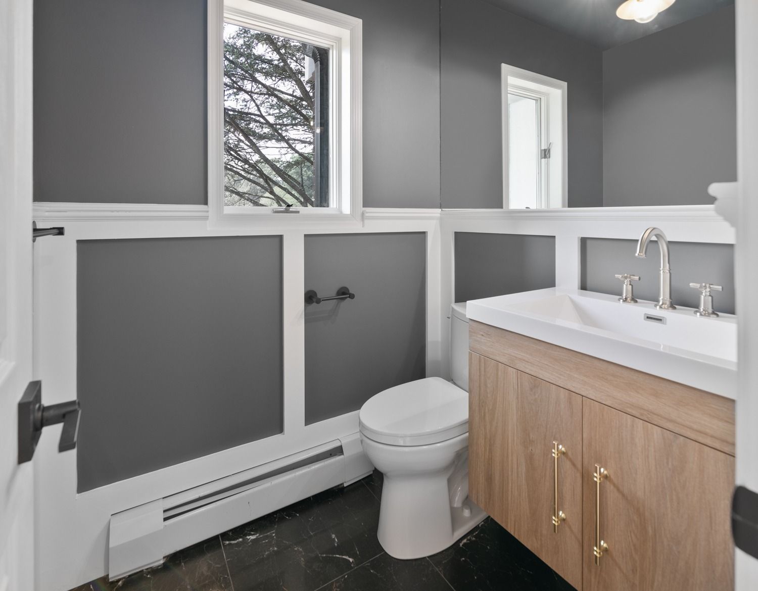 Gray and white bathroom with a toilet, sink, and window.