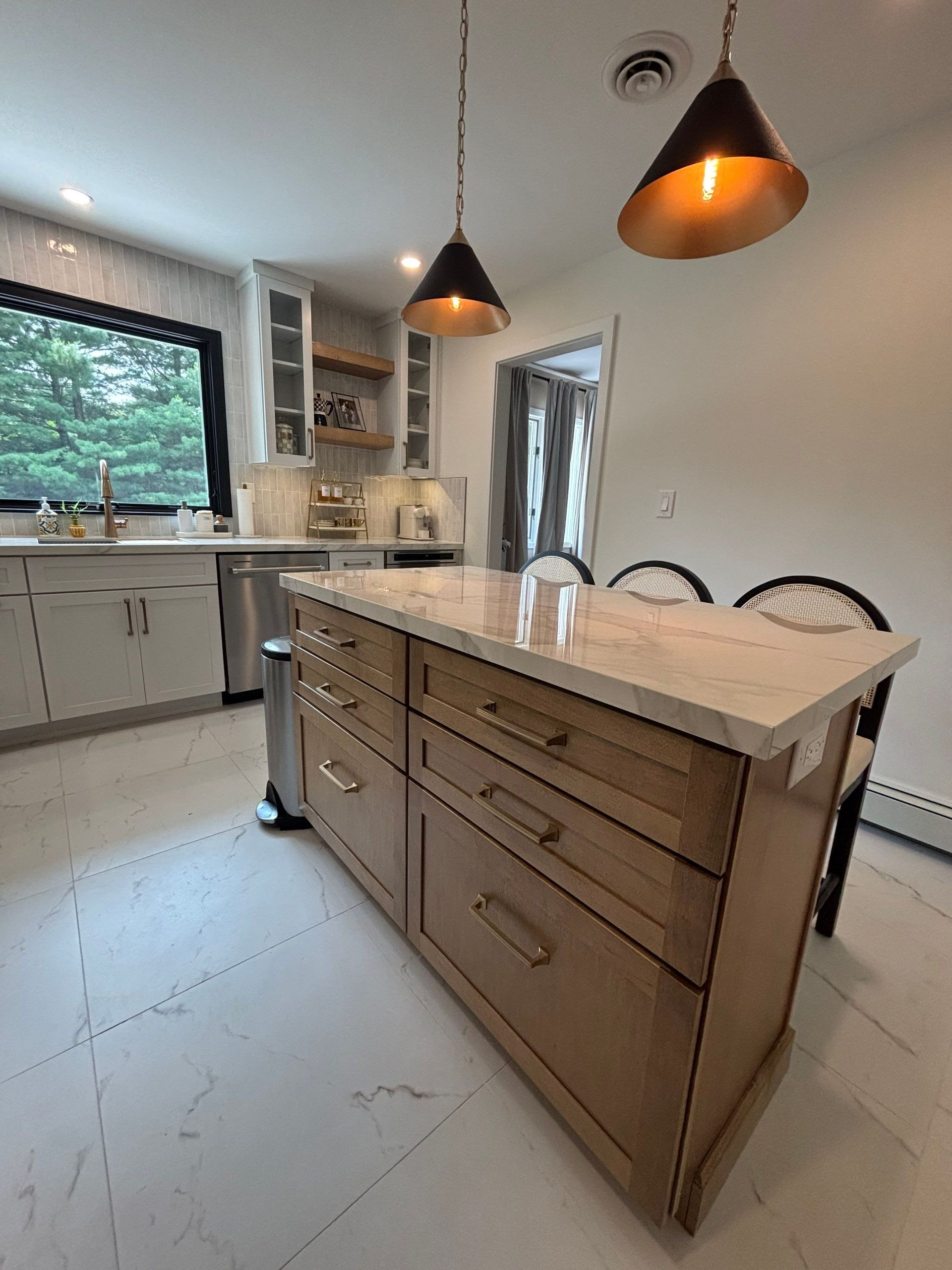 Kitchen with light wood island, drawers, pendant lights, and stainless steel appliances.