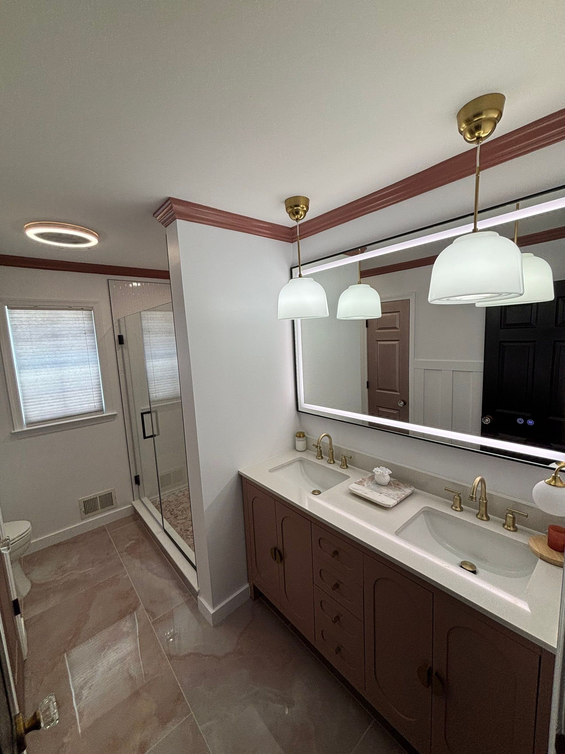 Modern bathroom with a double vanity, large mirror, and pendant lights.