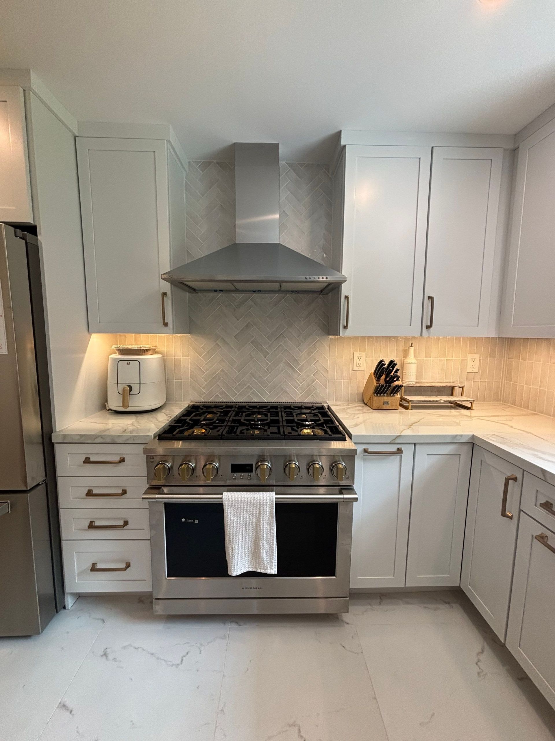 White kitchen with stainless steel appliances, white cabinets, and a gas range.
