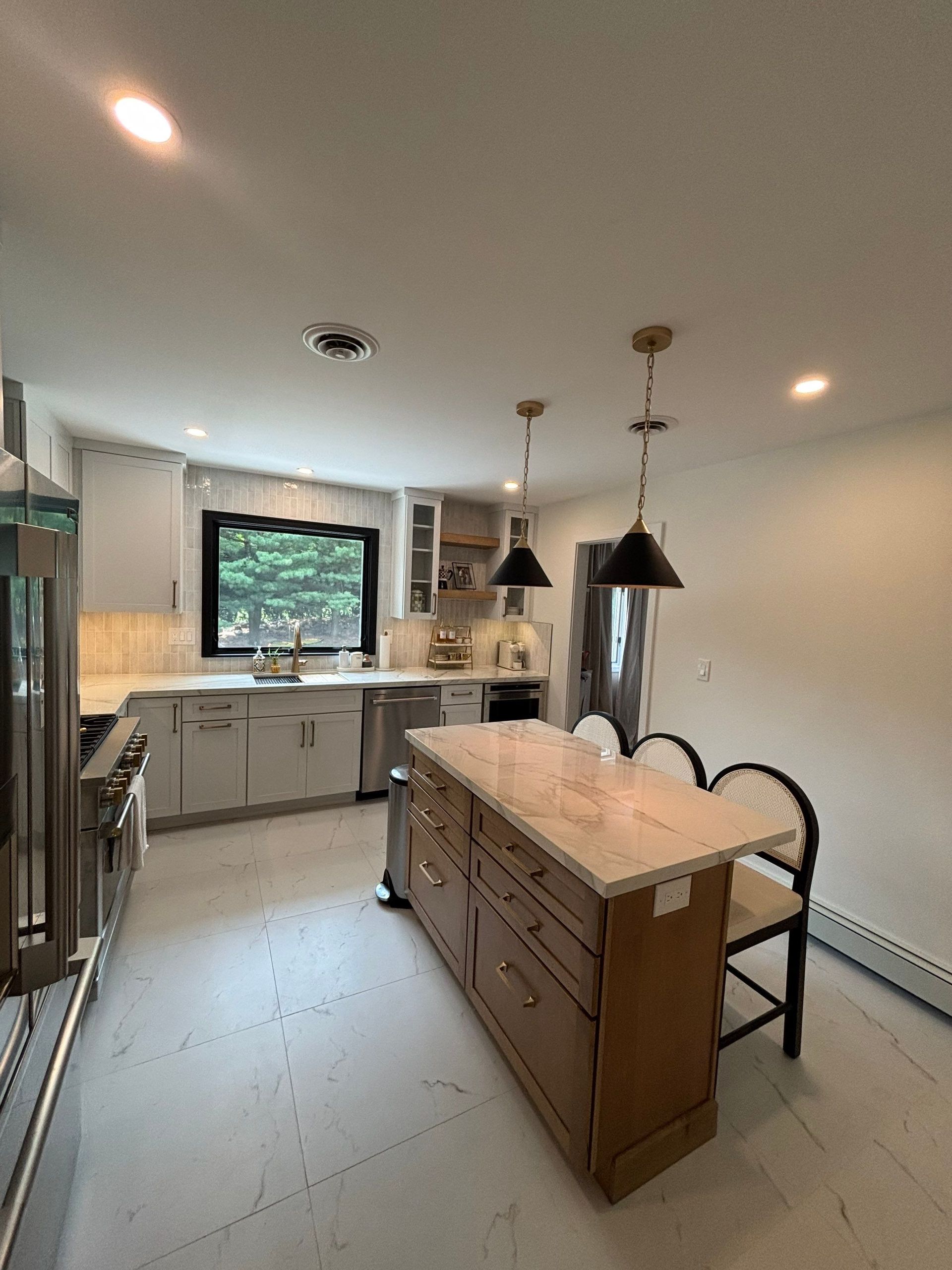 Modern kitchen with island, cabinets, countertops, and pendant lights.