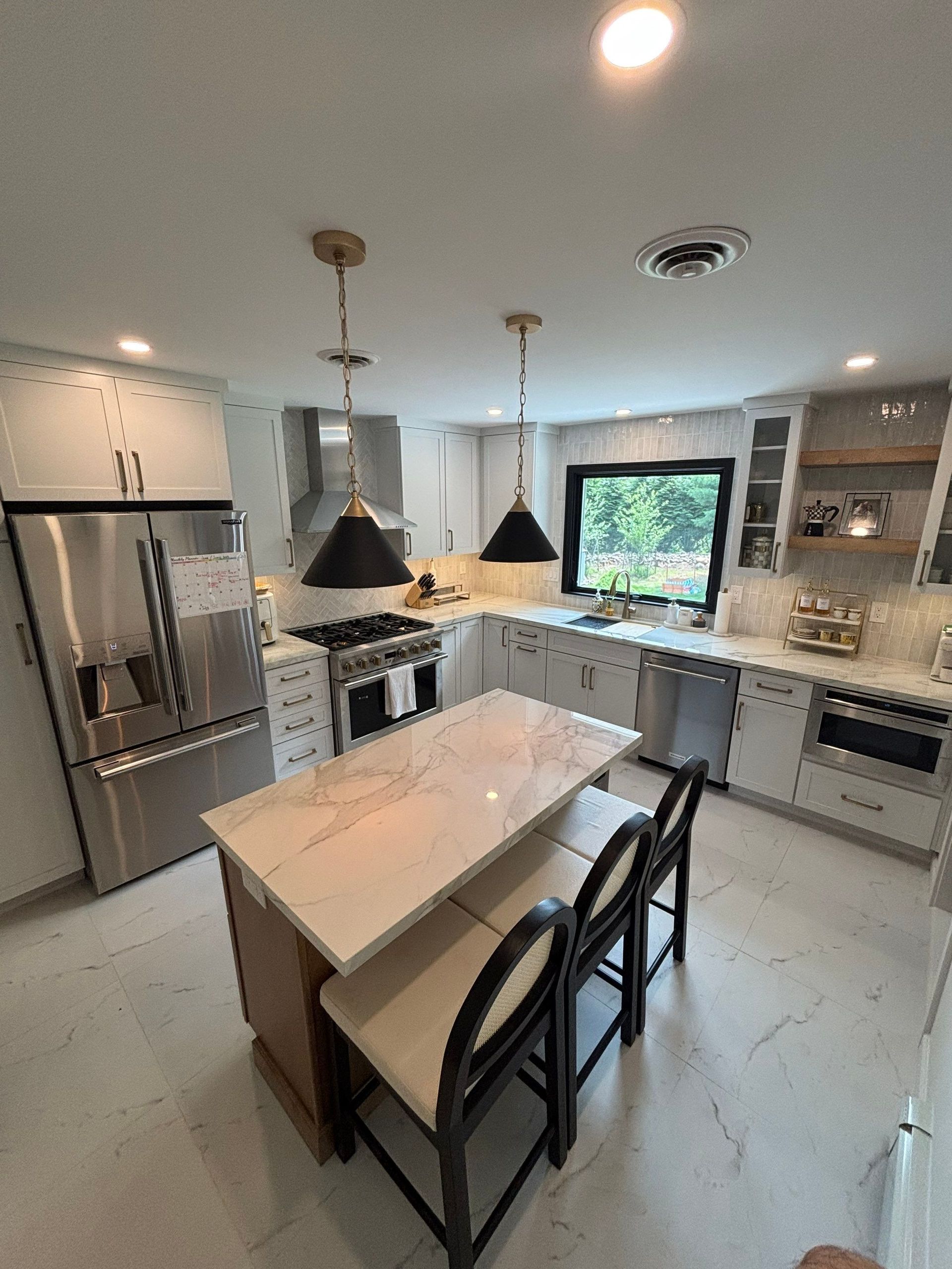 Modern kitchen with island, stainless steel appliances, and two pendant lights.