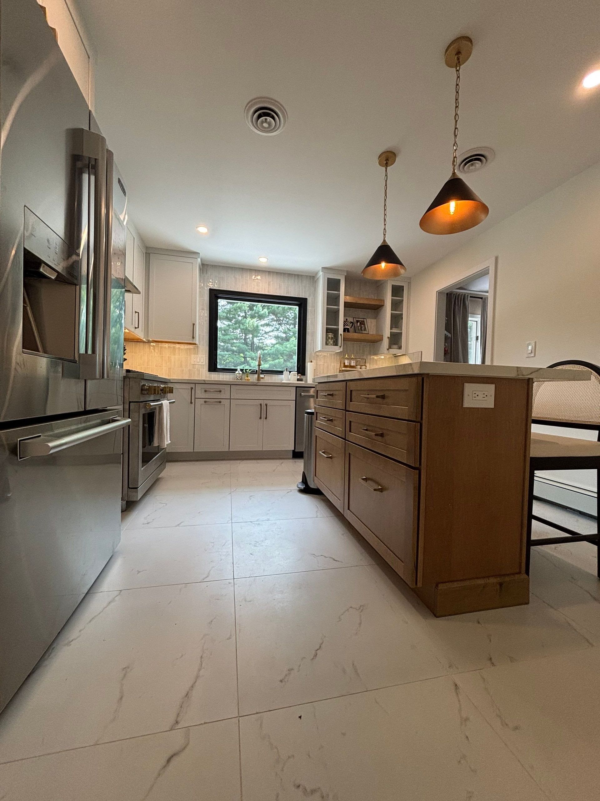 Kitchen with stainless steel appliances, light gray cabinets, and a wooden island. White tiled floor.