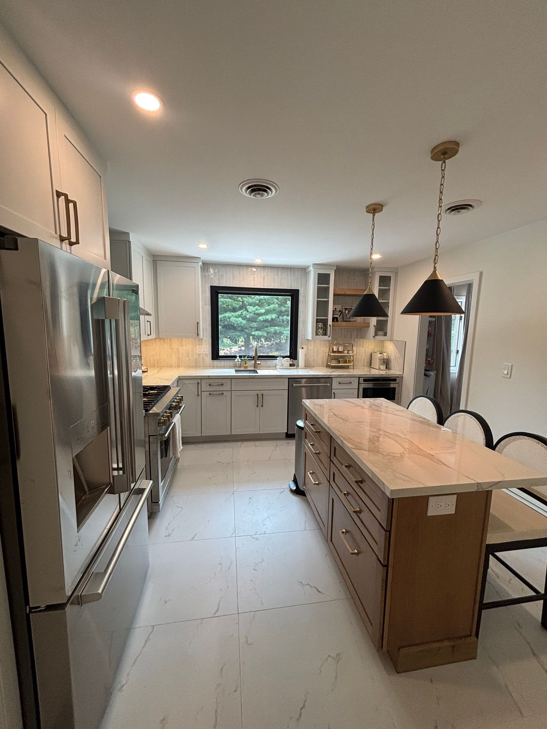Modern kitchen with light gray cabinets, stainless steel appliances, and an island with a light countertop.