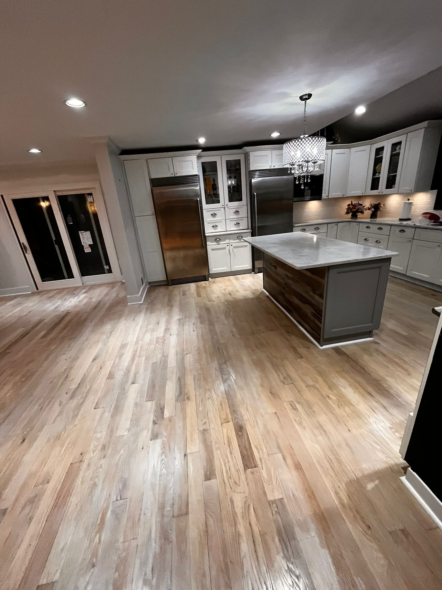 Spacious kitchen with wood floors, island, stainless steel appliances, and white cabinets.