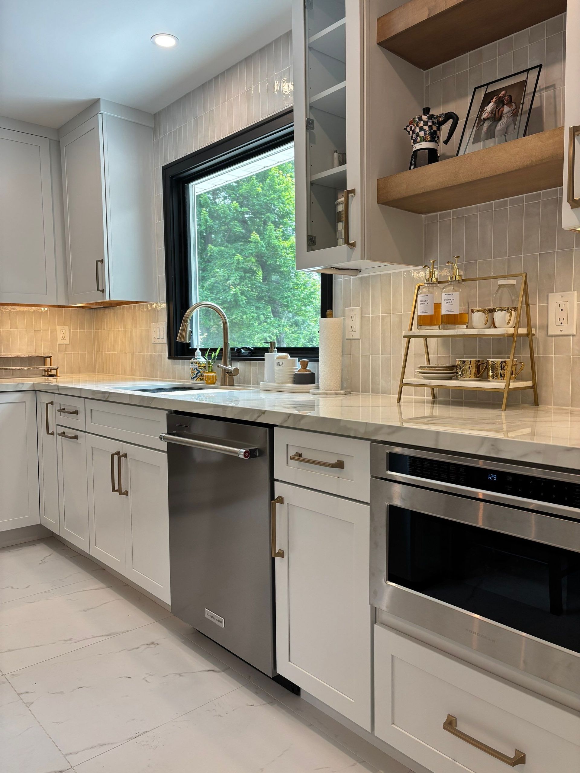 White kitchen with stainless steel appliances, open window, and wood shelving.