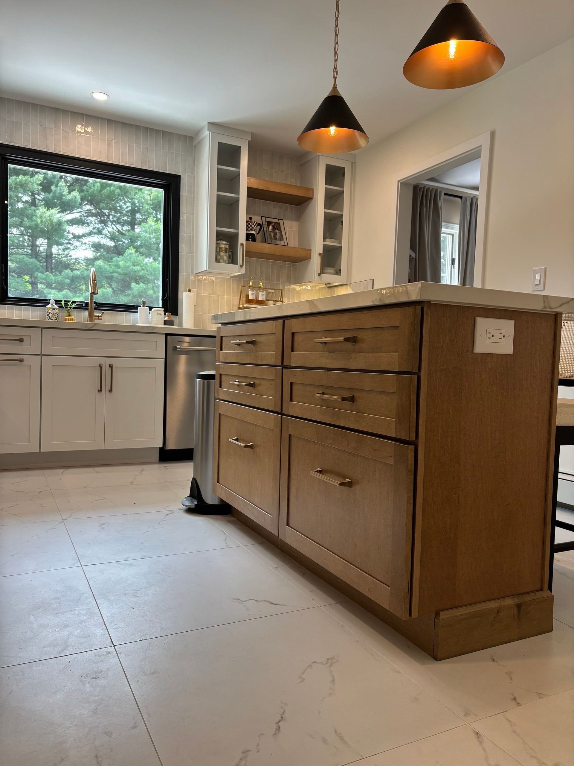 Kitchen with light-colored cabinets and island, stainless steel appliances, and pendant lights.