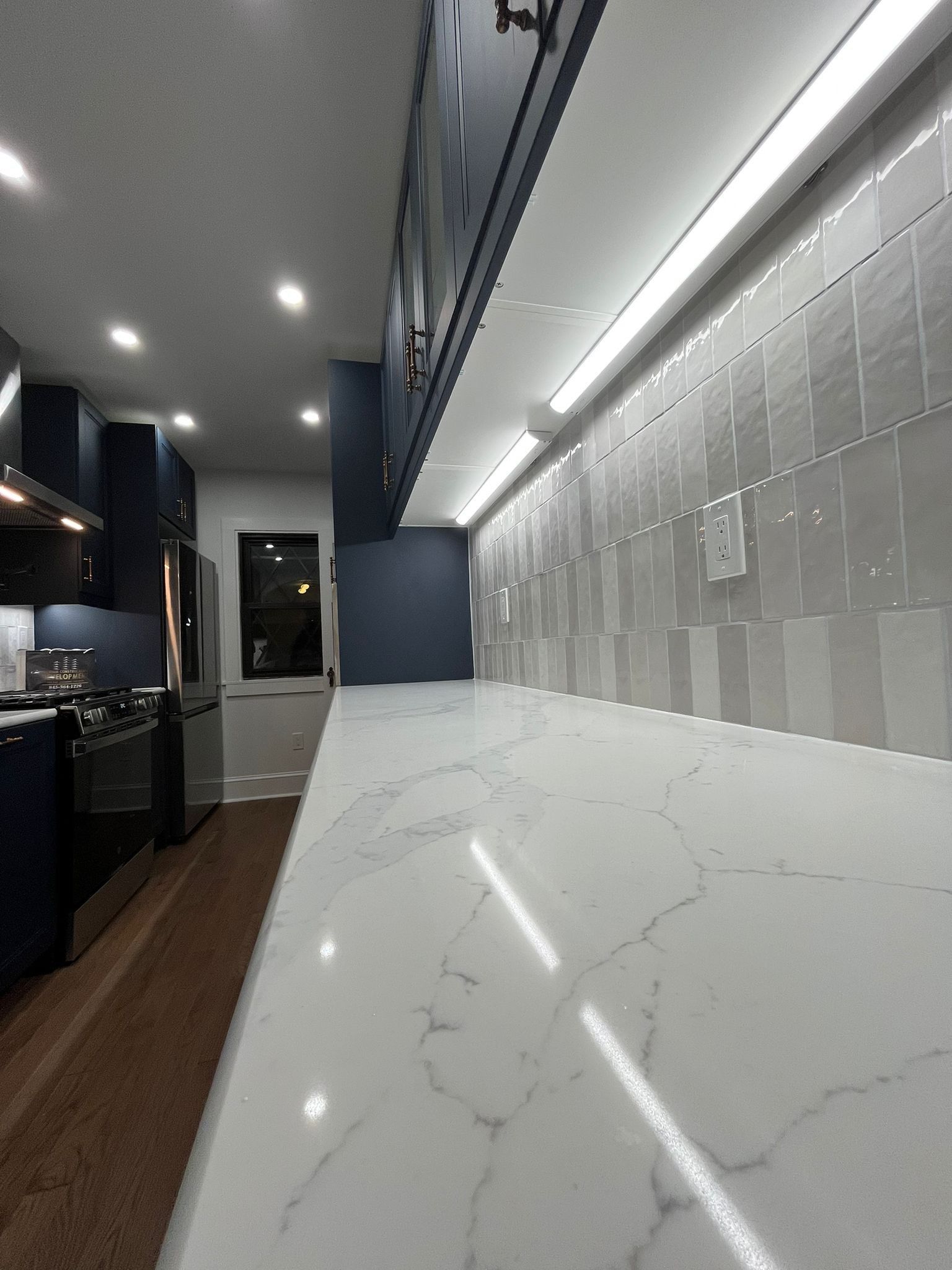 Modern kitchen with a white marble countertop and gray tiled backsplash.
