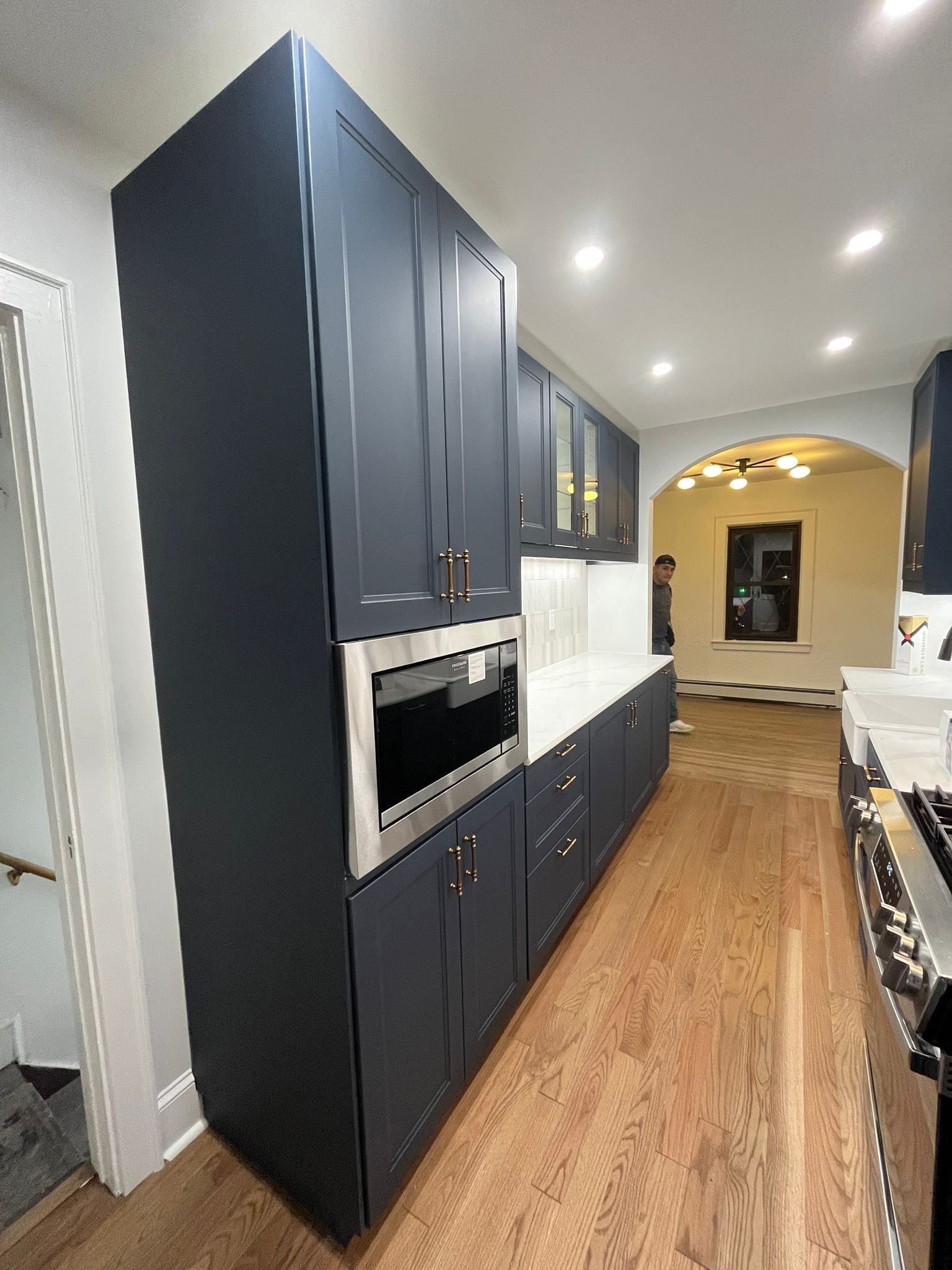 Blue kitchen cabinets with built-in microwave, white countertops, and hardwood floors.