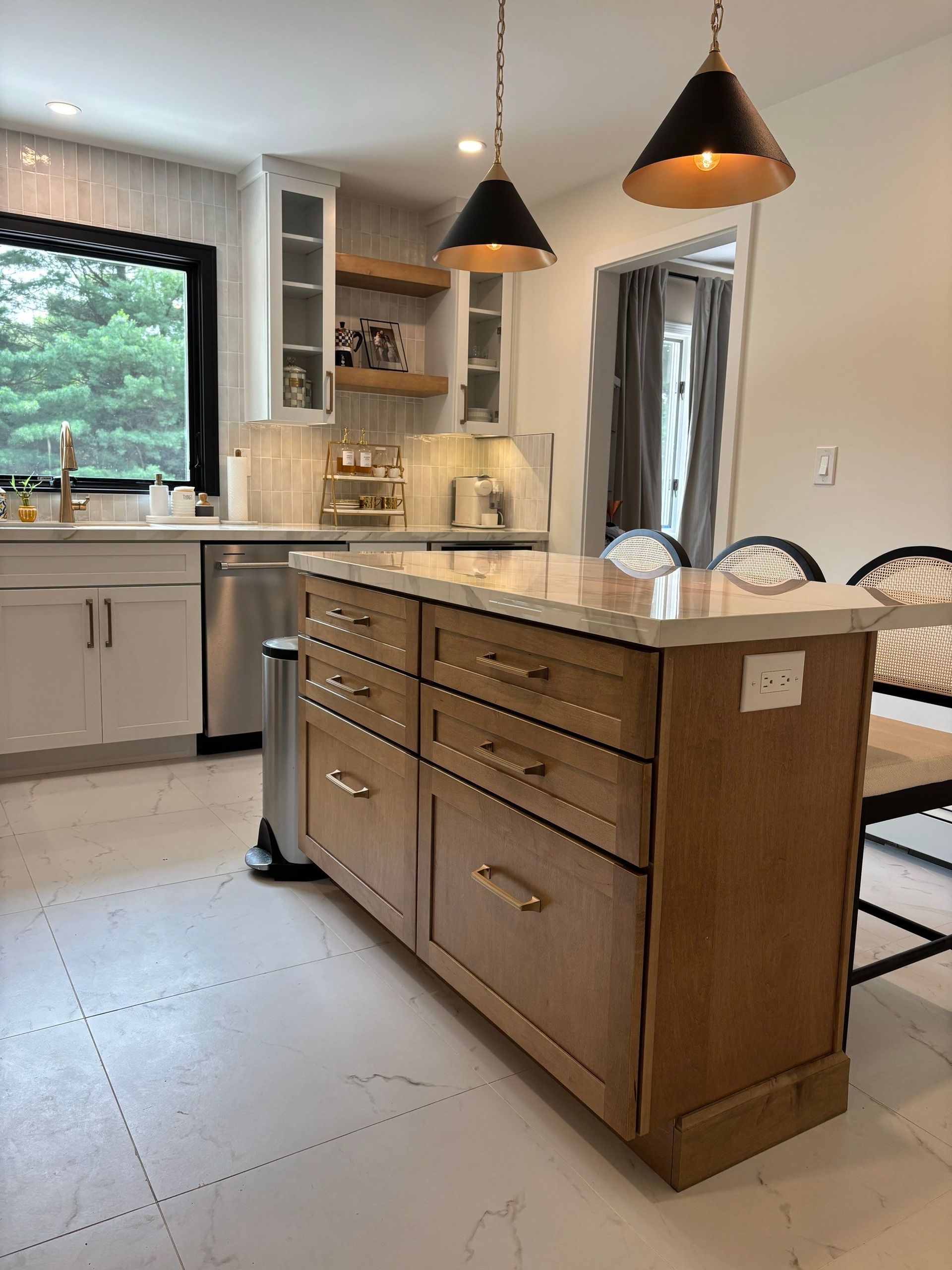 Kitchen with light wood island, drawers, pendant lights, and stainless steel appliances.