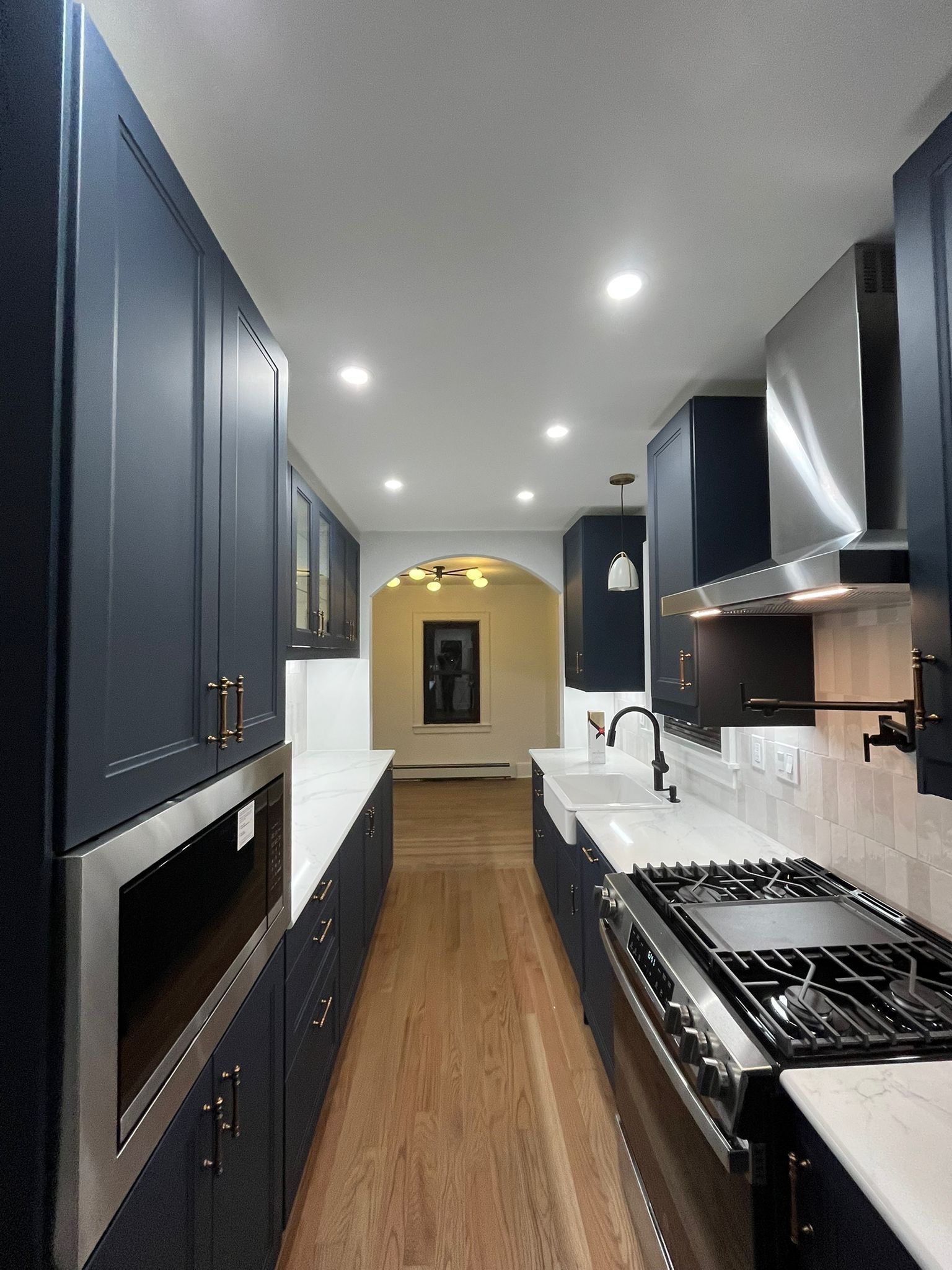 Dark blue kitchen with white countertops and stainless steel appliances.