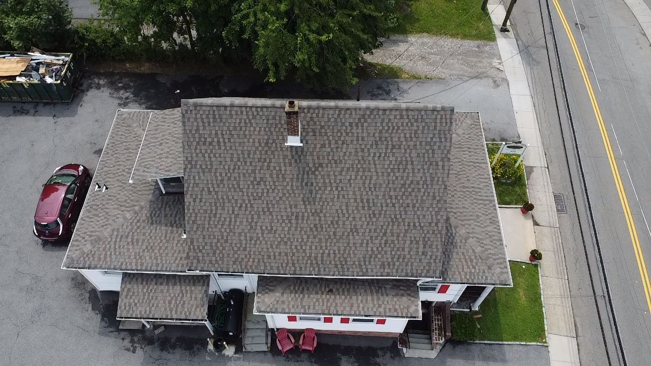 Overhead view of a building with a gray roof and a red car parked nearby.