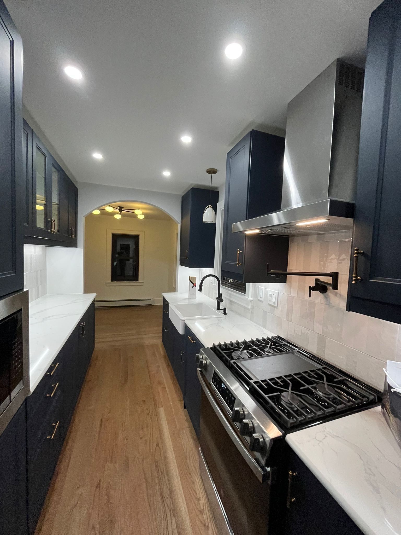 Navy blue kitchen with white countertops and stainless steel appliances.