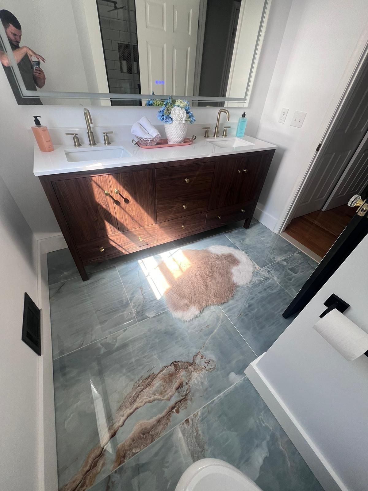 Bathroom with dark wood vanity, patterned blue-gray floor, and a brown rug.
