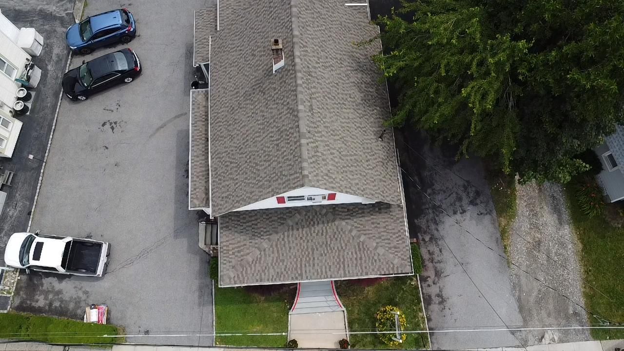 Overhead view of a building with a gray roof and cars parked on the side.