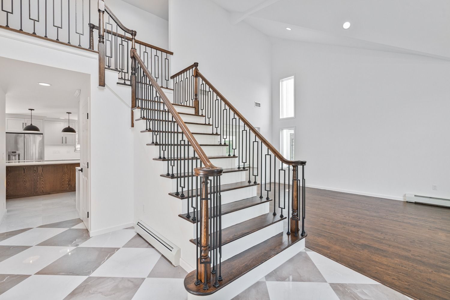 Staircase with dark wood steps and railing, black iron balusters, and checkered tile floor.