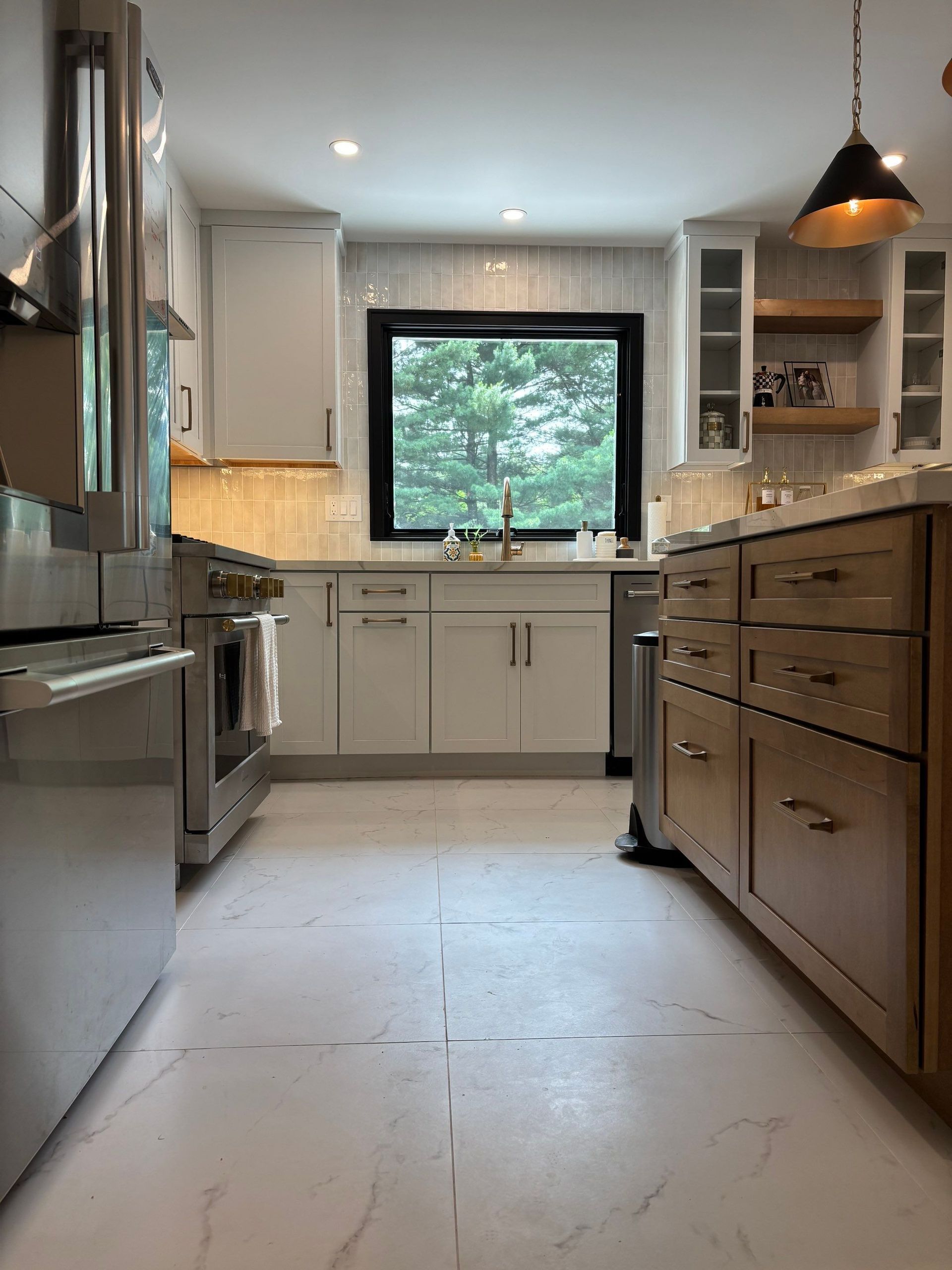 Kitchen with white cabinets, stainless steel appliances, and island with wood-tone cabinets.