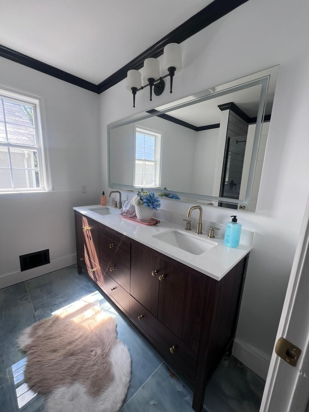 Bathroom with dark wood double vanity, white countertop, large mirror, and black trim.