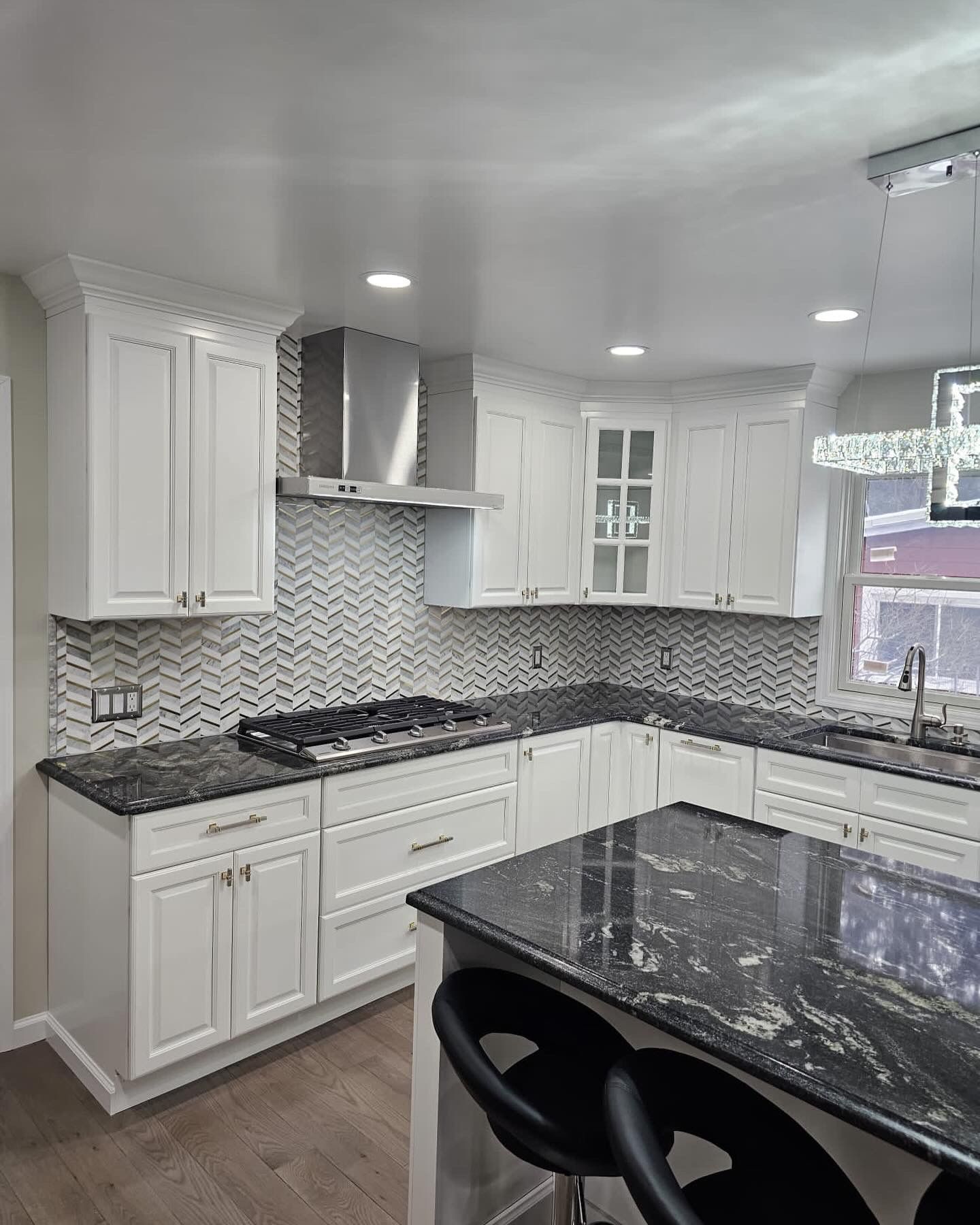 White kitchen with black countertops, stainless steel appliances, and a tiled backsplash.