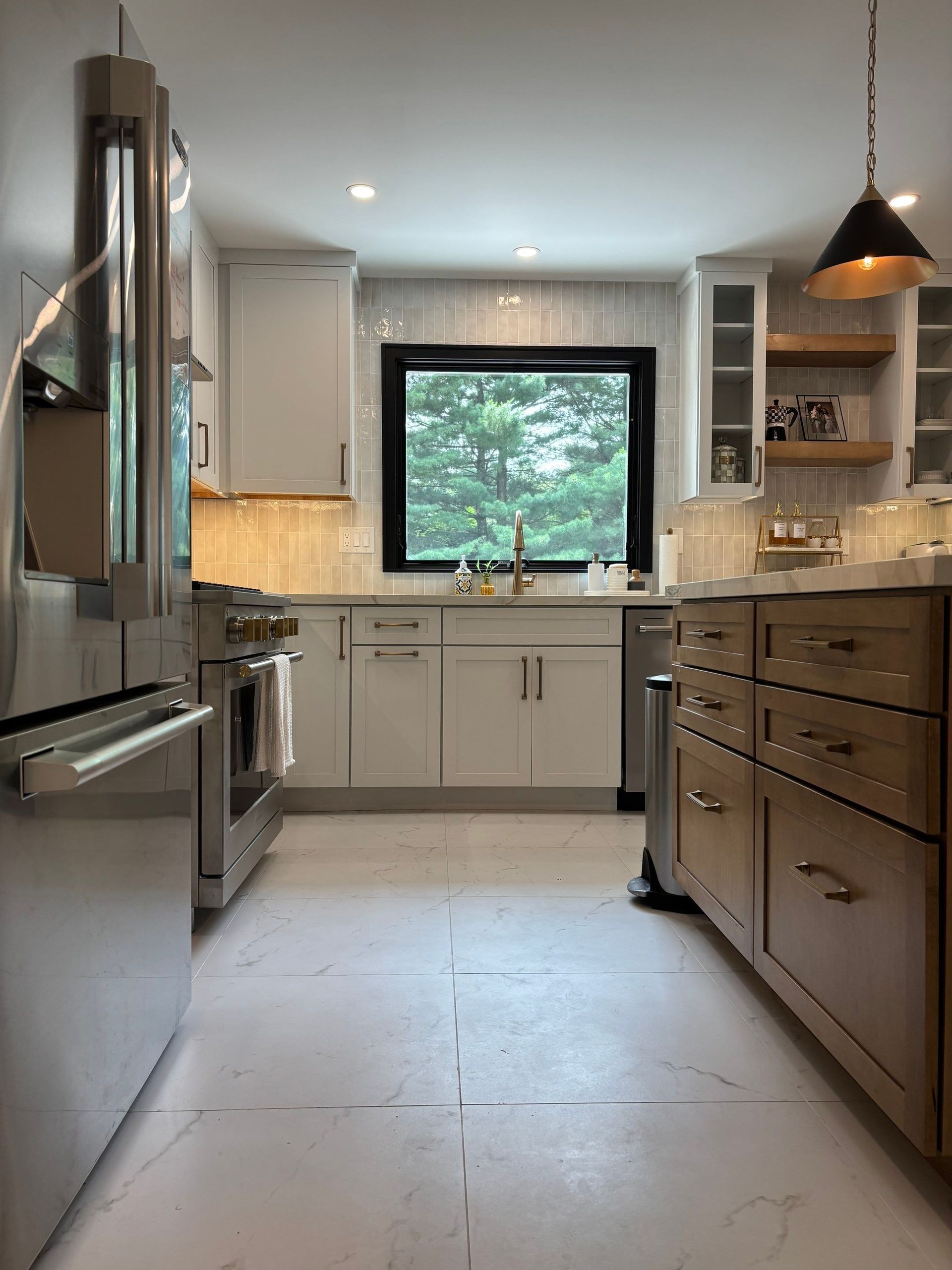 Modern kitchen with white cabinets, stainless steel appliances, and a dark-framed window.