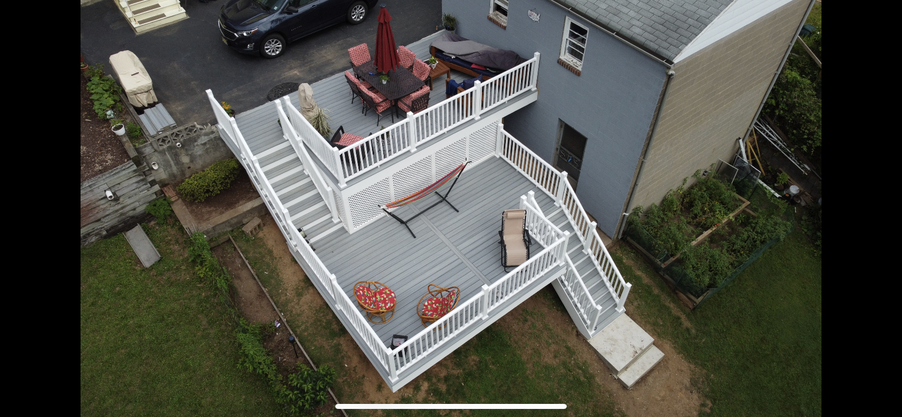 Aerial view of a multi-level deck with white railings, gray decking, and patio furniture.