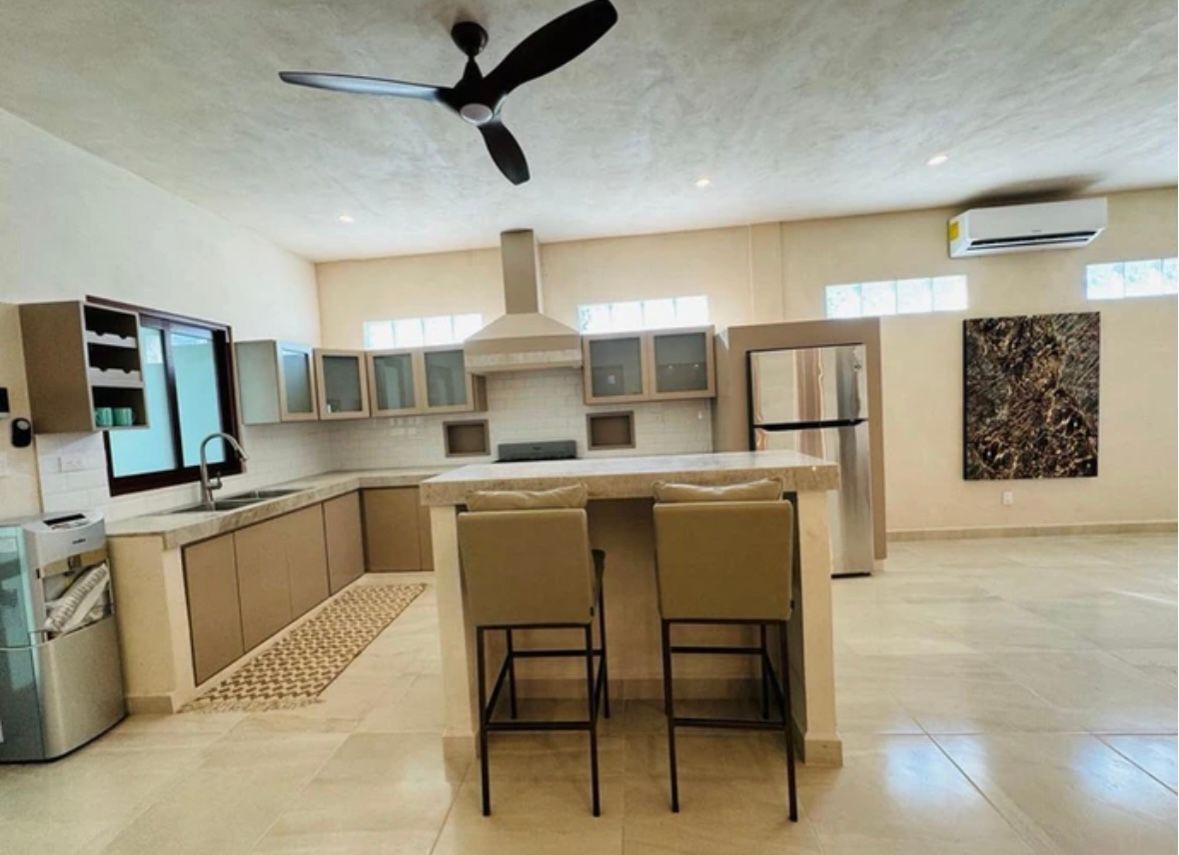 Modern kitchen with island, cabinets, stainless steel appliances, and two bar stools.