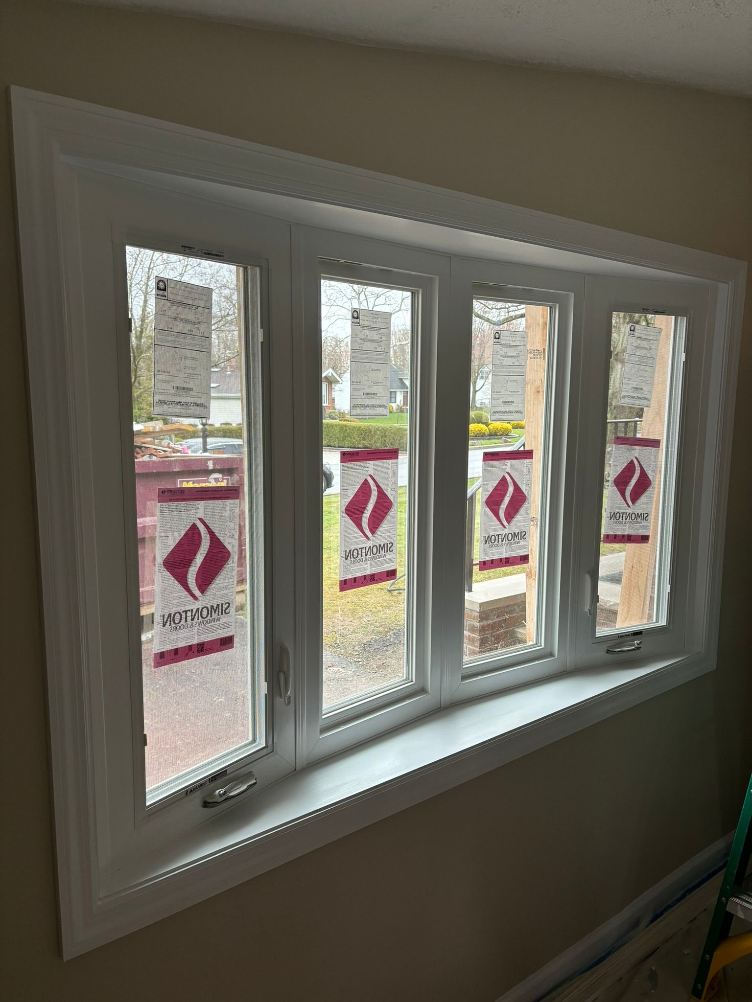 White bay window with protective wrapping and white trim, installed on a beige wall.