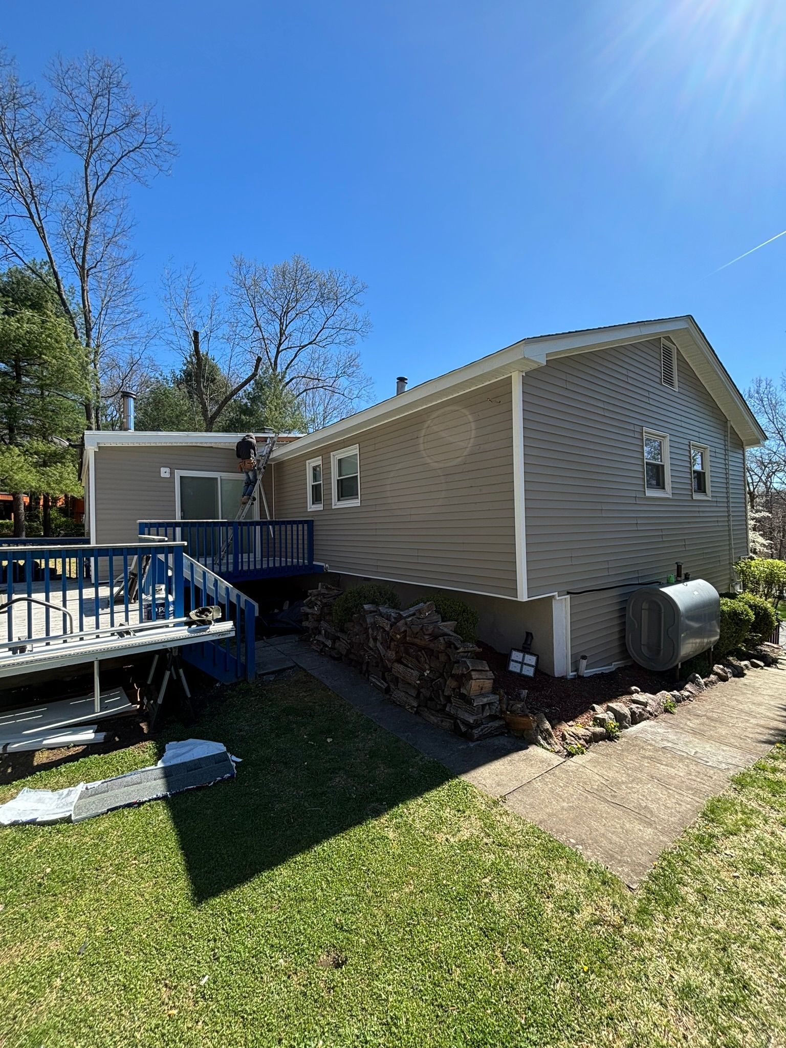 House with gray siding and blue deck on a sunny day.