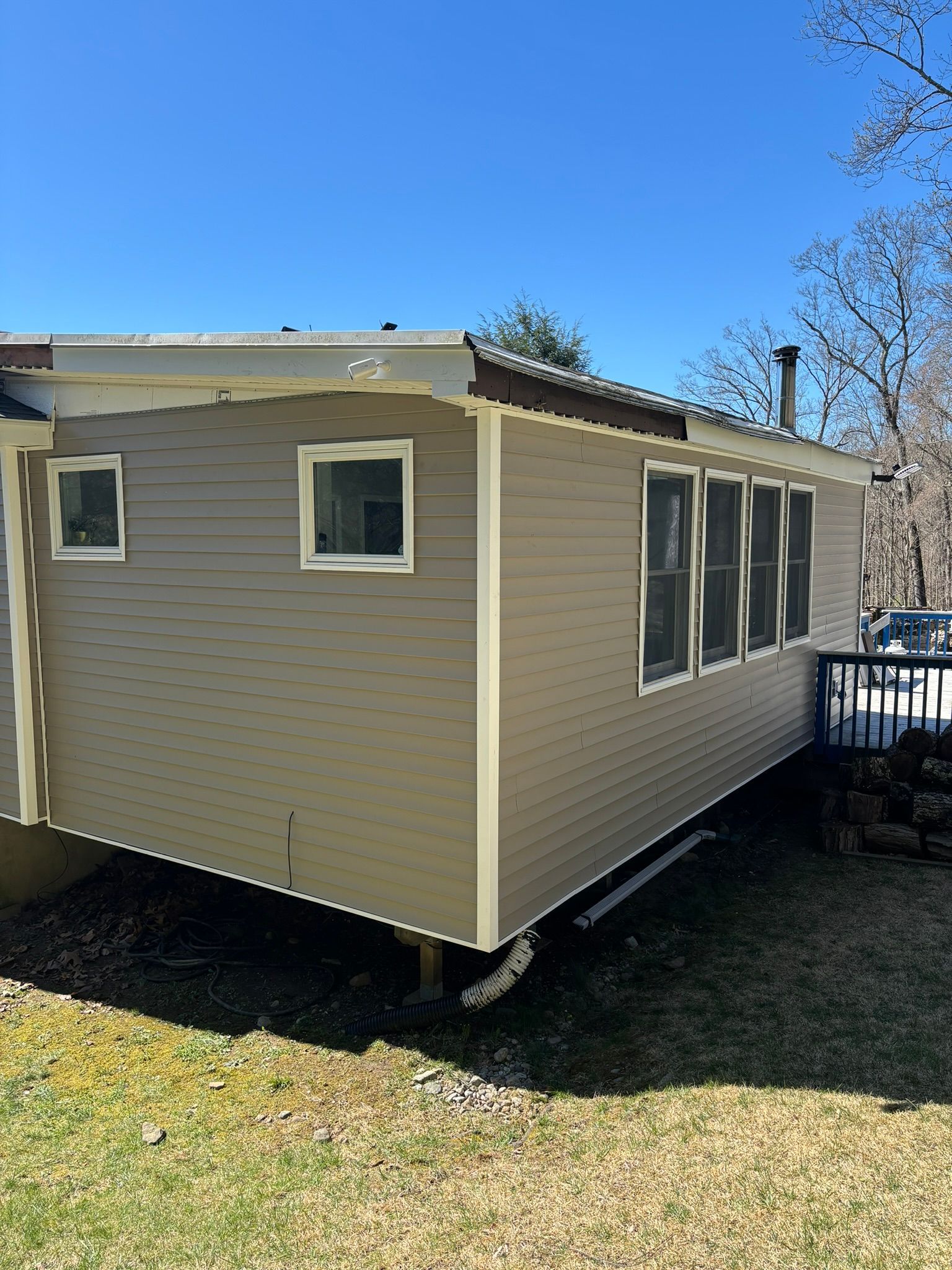 Tan building with white trim, windows, and dark roof under a blue sky.