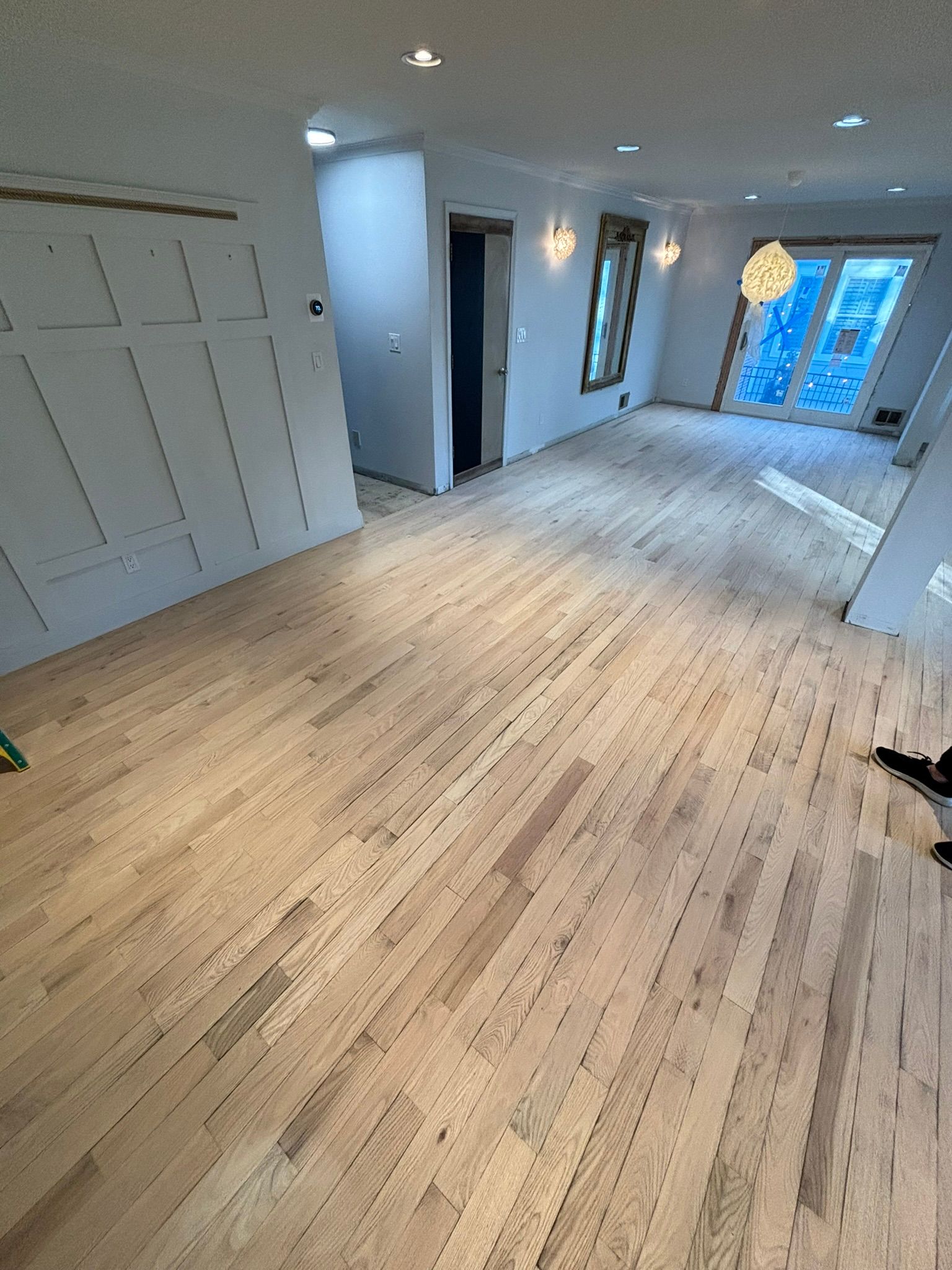 Newly installed hardwood floors in an empty room, with unfinished walls and an open doorway.