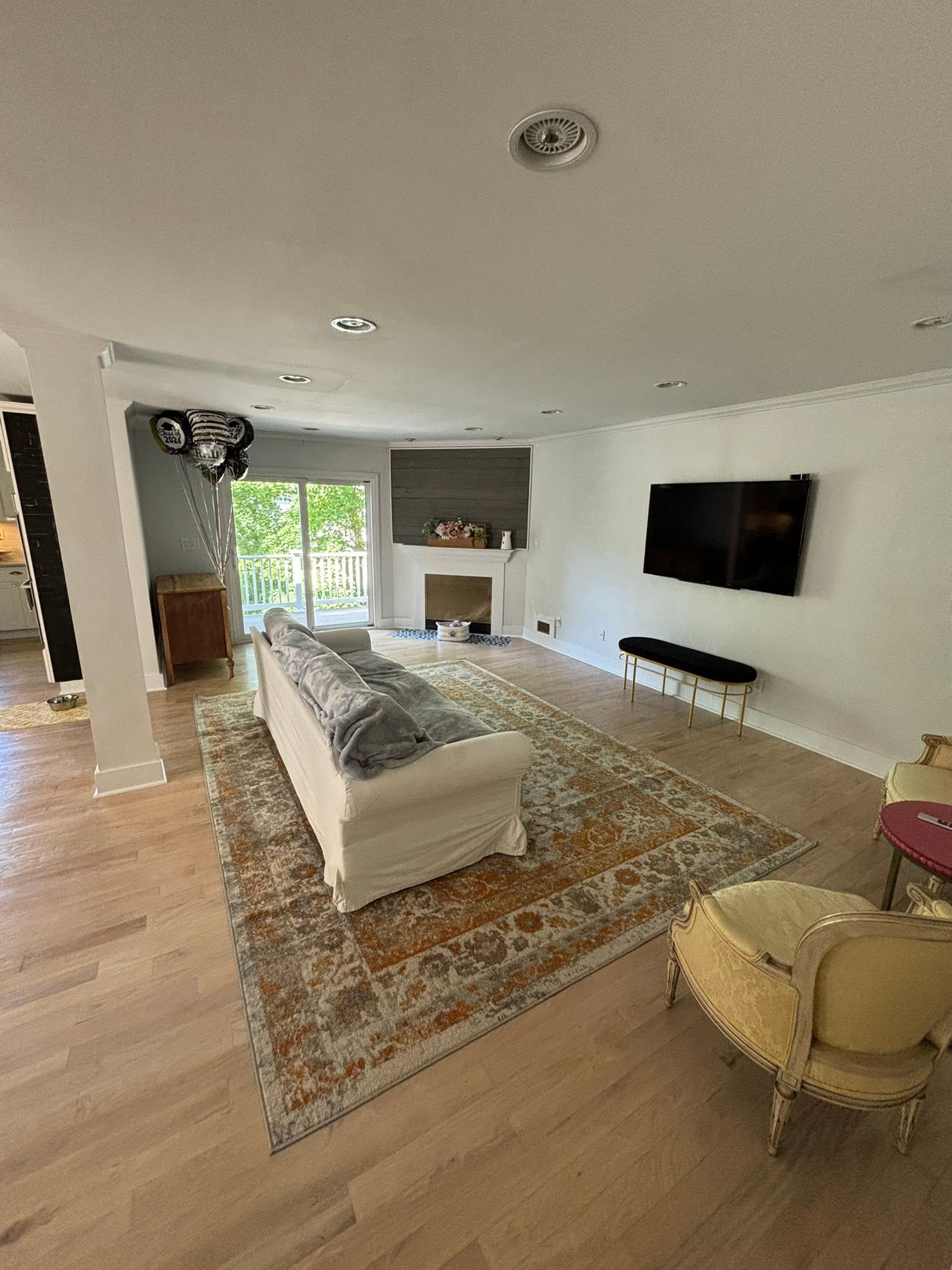 Living room with a white sofa on a large rug, TV on the wall, and fireplace.